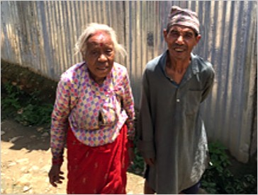 Quake survivors stand near a temporary tin shelter